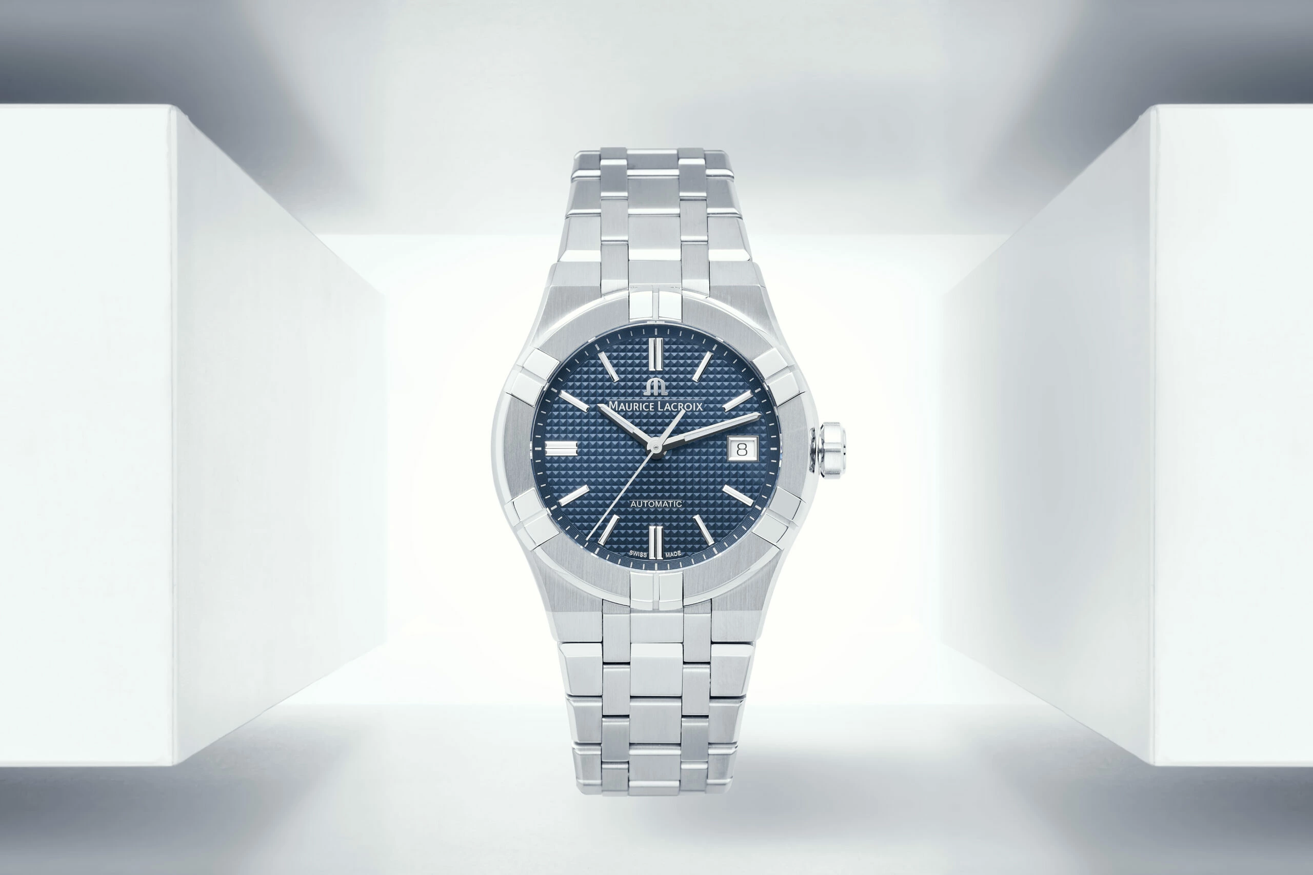 Photo de produit centrée d'une montre-bracelet argentée avec cadran texturé bleu, affichage de la date et marque Chronomètre de Luxe Paris sur fond blanc-gris.