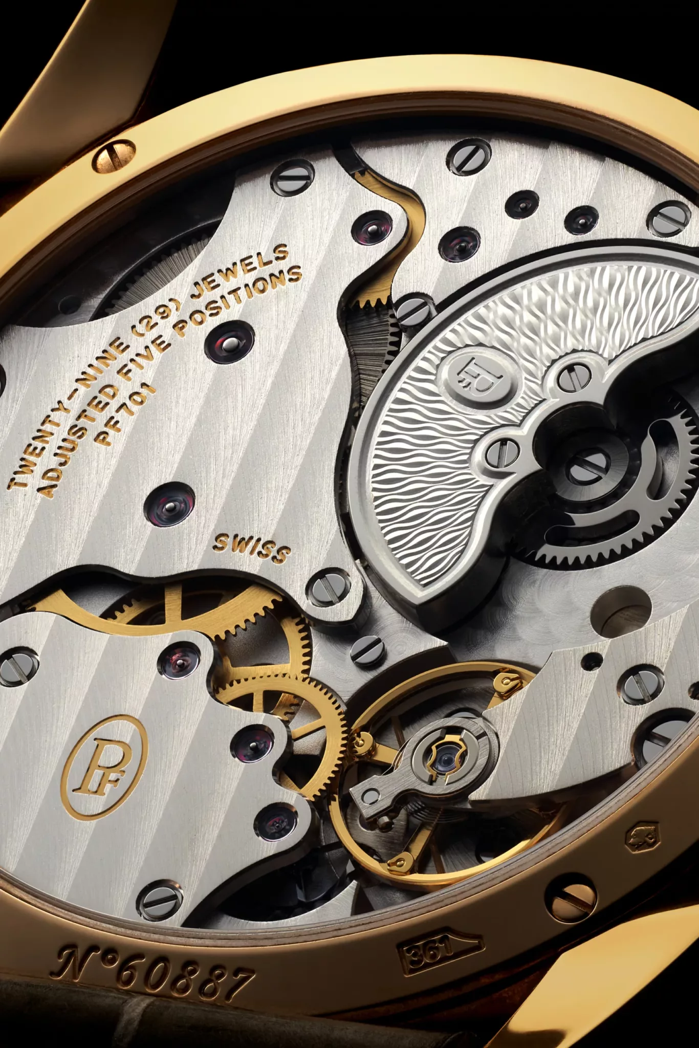 agence de photographie rétines – horlogerie Parmigiani-HD-02-1 2 Macro prise de vue d'un mouvement de montre montrant les engrenages, les vis et le rotor en métal gravé avec 23 JEWELS, SWISS, et le numéro de série N°60887.