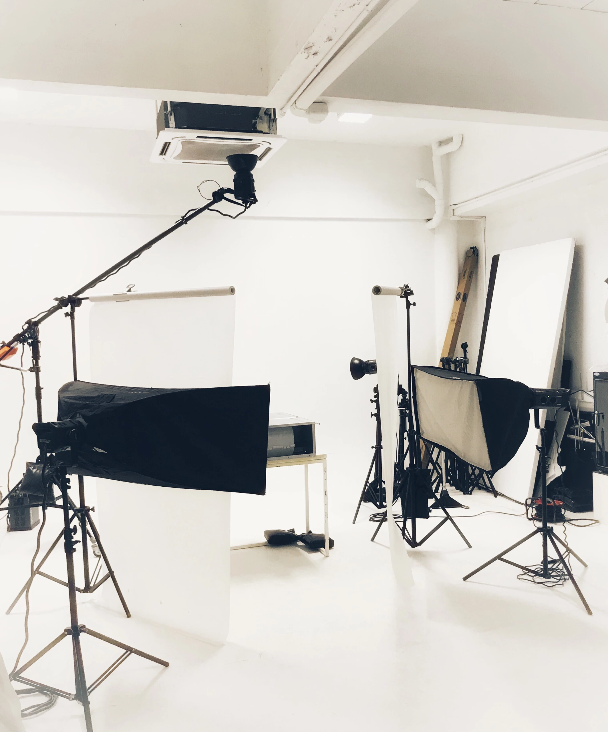 Studio professionnel avec toiles de fond blanches, éclairage par boîte à lumière sur trépieds, microphone à perche et matériel Ooshot dans un espace de travail bien éclairé.