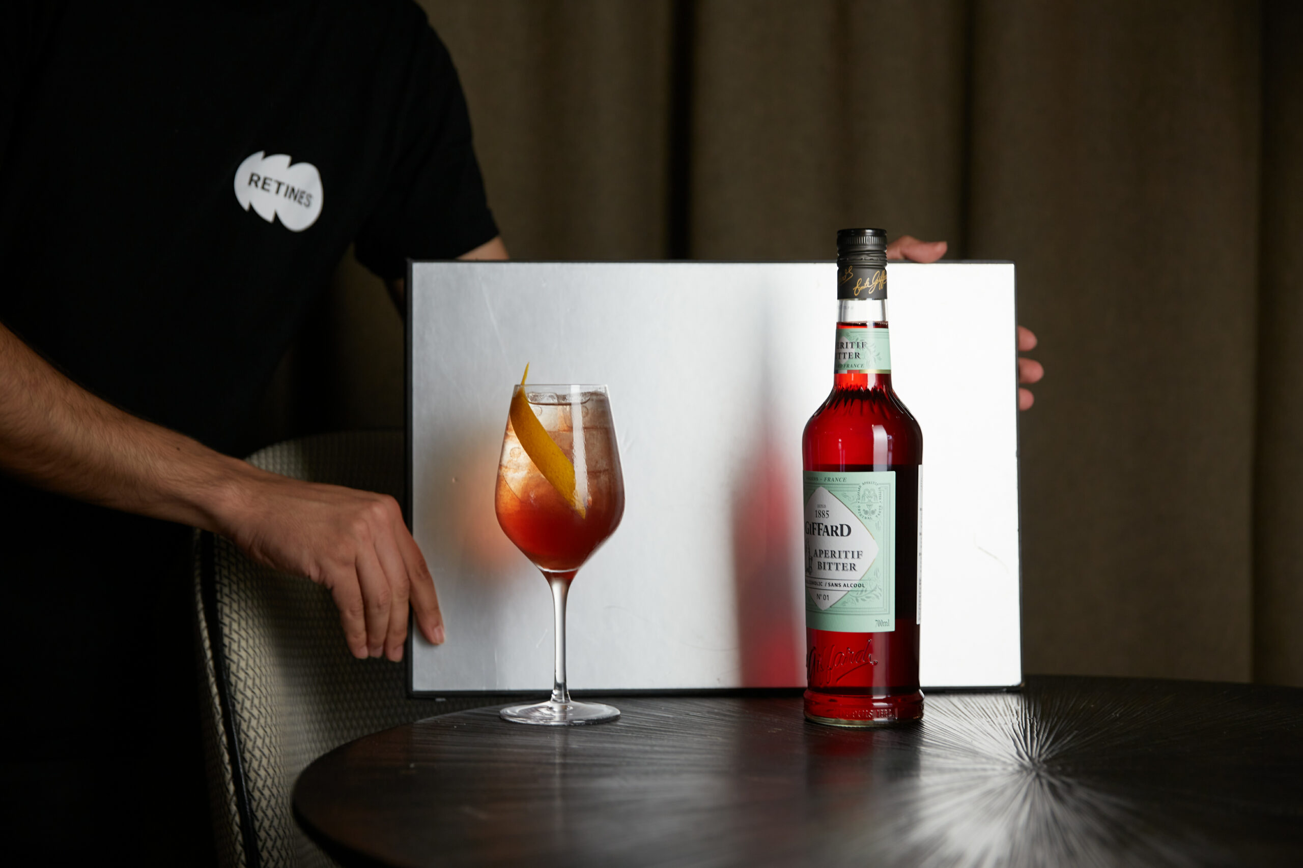 Photographe tenant un réflecteur pendant un shooting spiritueux