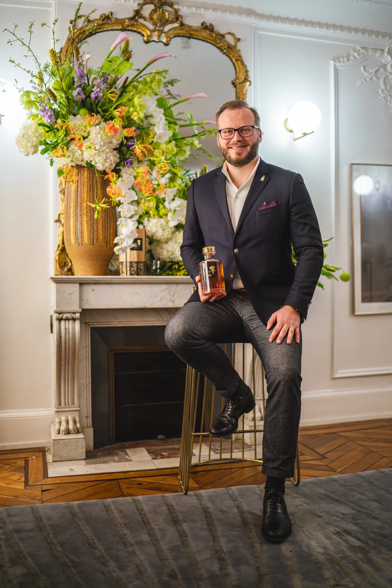 Personne tenant une bouteille de whisky Hibiki assis sur une chaise