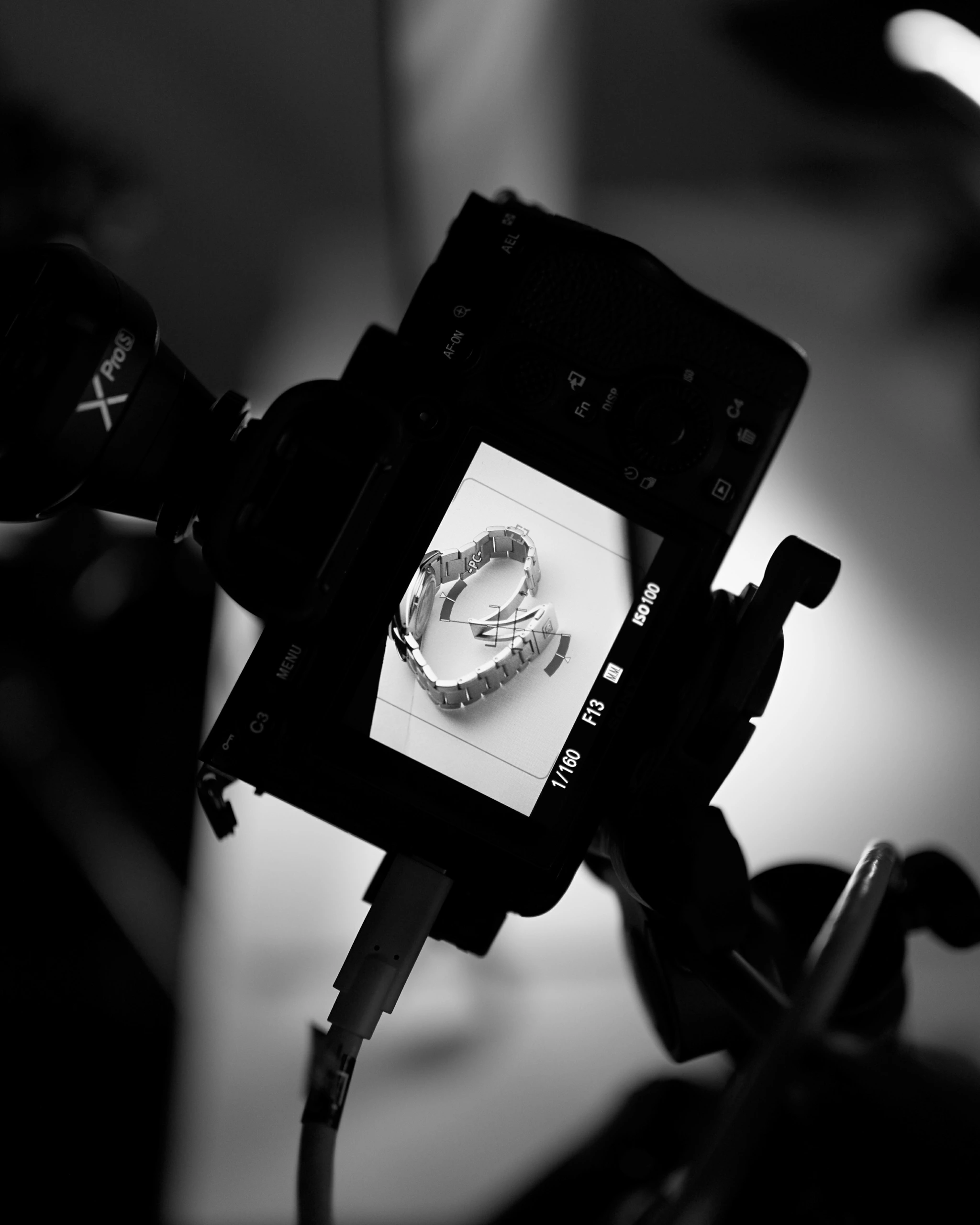Un appareil photo LCD affiche un gros plan monochrome de deux montres-bracelets disposées en cœur, illustrant les techniques de retouche photographique.