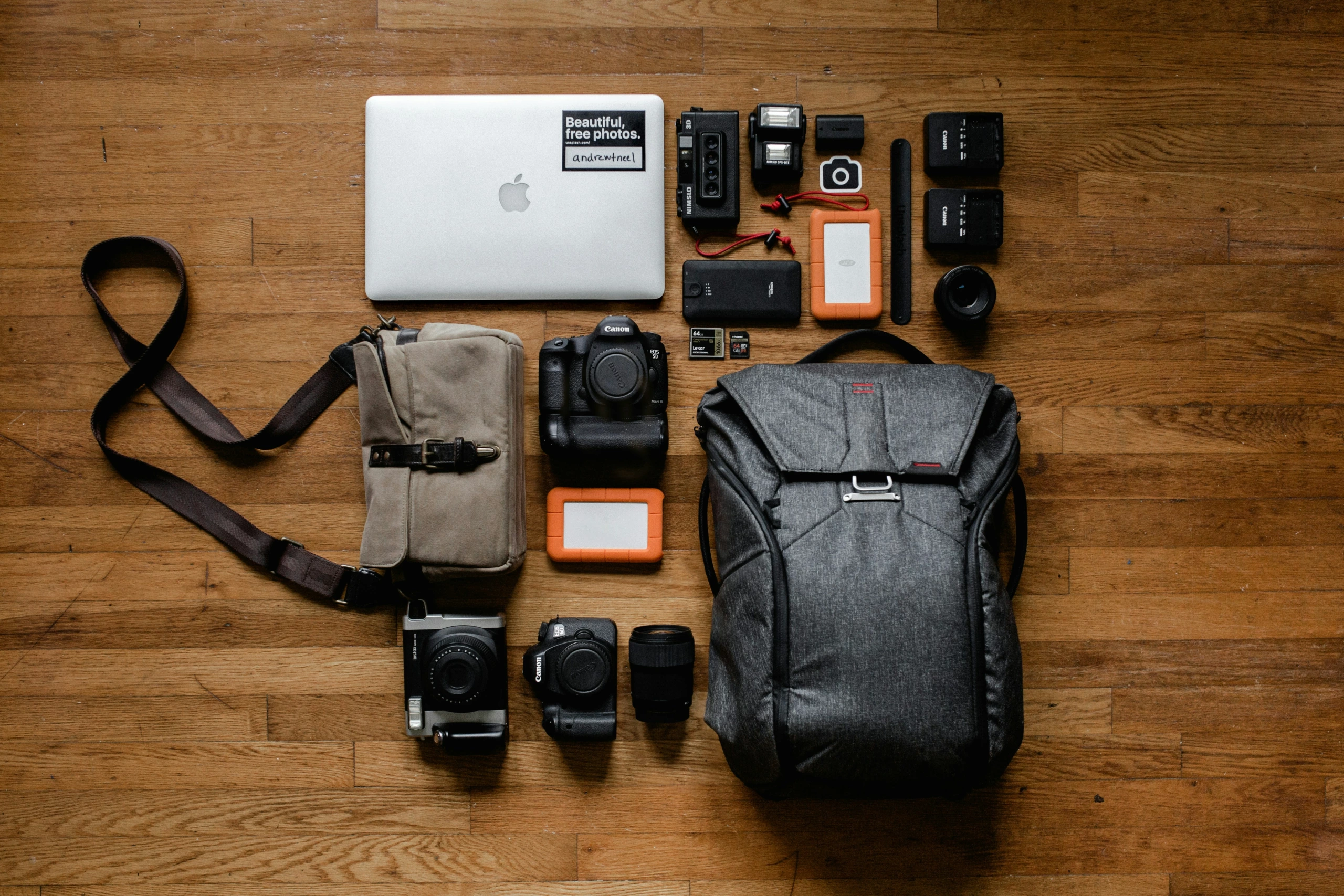 Mise à plat du matériel photographique professionnel : ordinateur portable, boîtiers d'appareils photo, objectifs, cartes mémoire, sacs, disque dur, batteries et chargeurs.