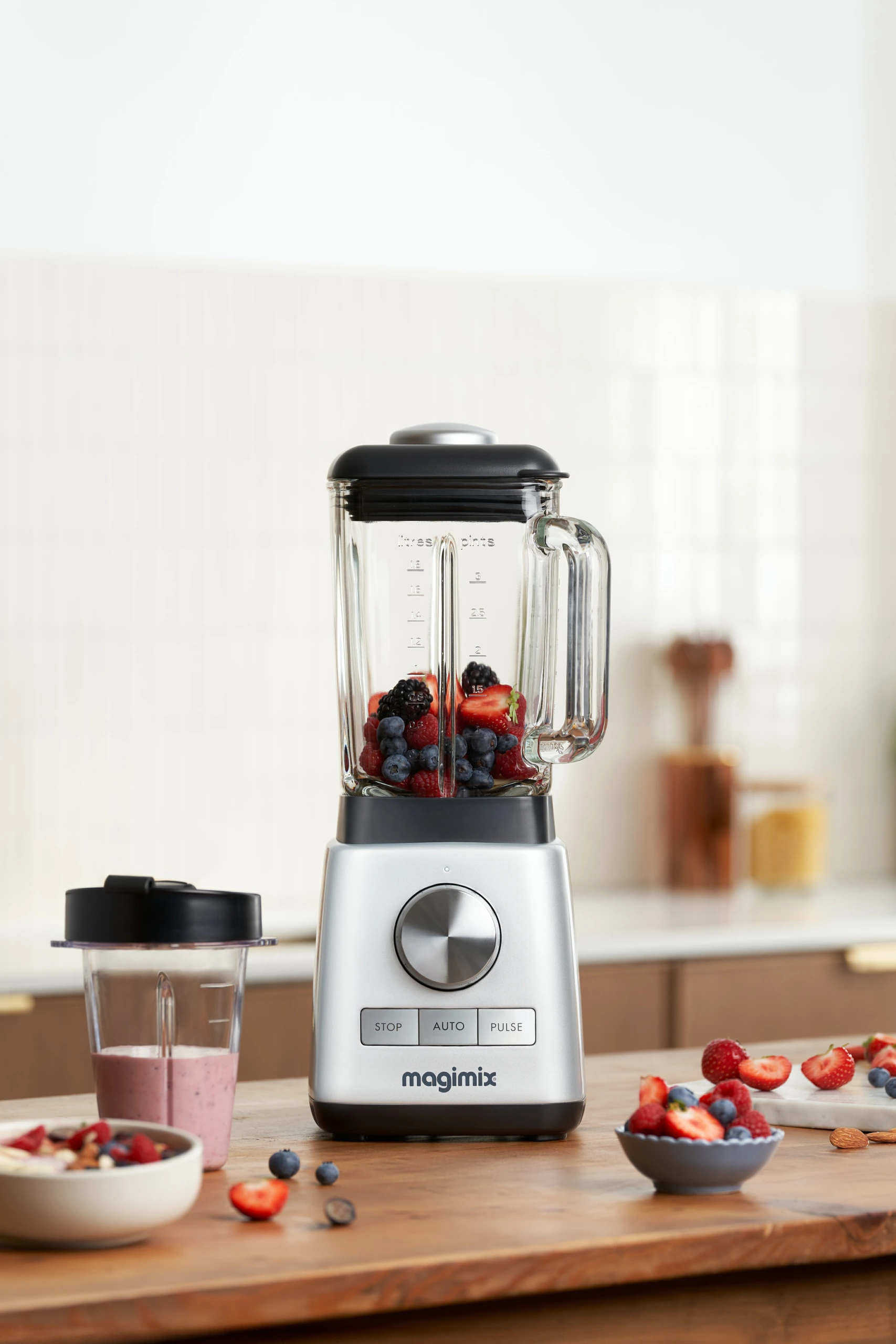 Blender Magimix rempli de fruits rouges et de myrtilles, photographié sur un plan de travail