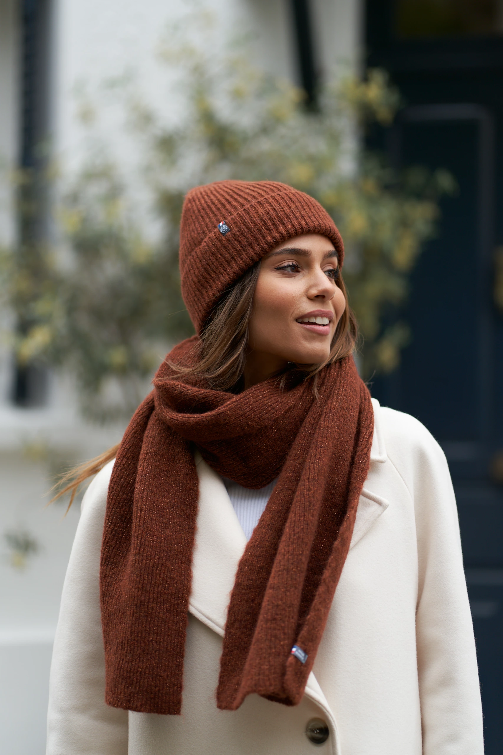 Portrait d’une femme portant un bonnet et des gants en laine marron de chez Maison Bonnefoy