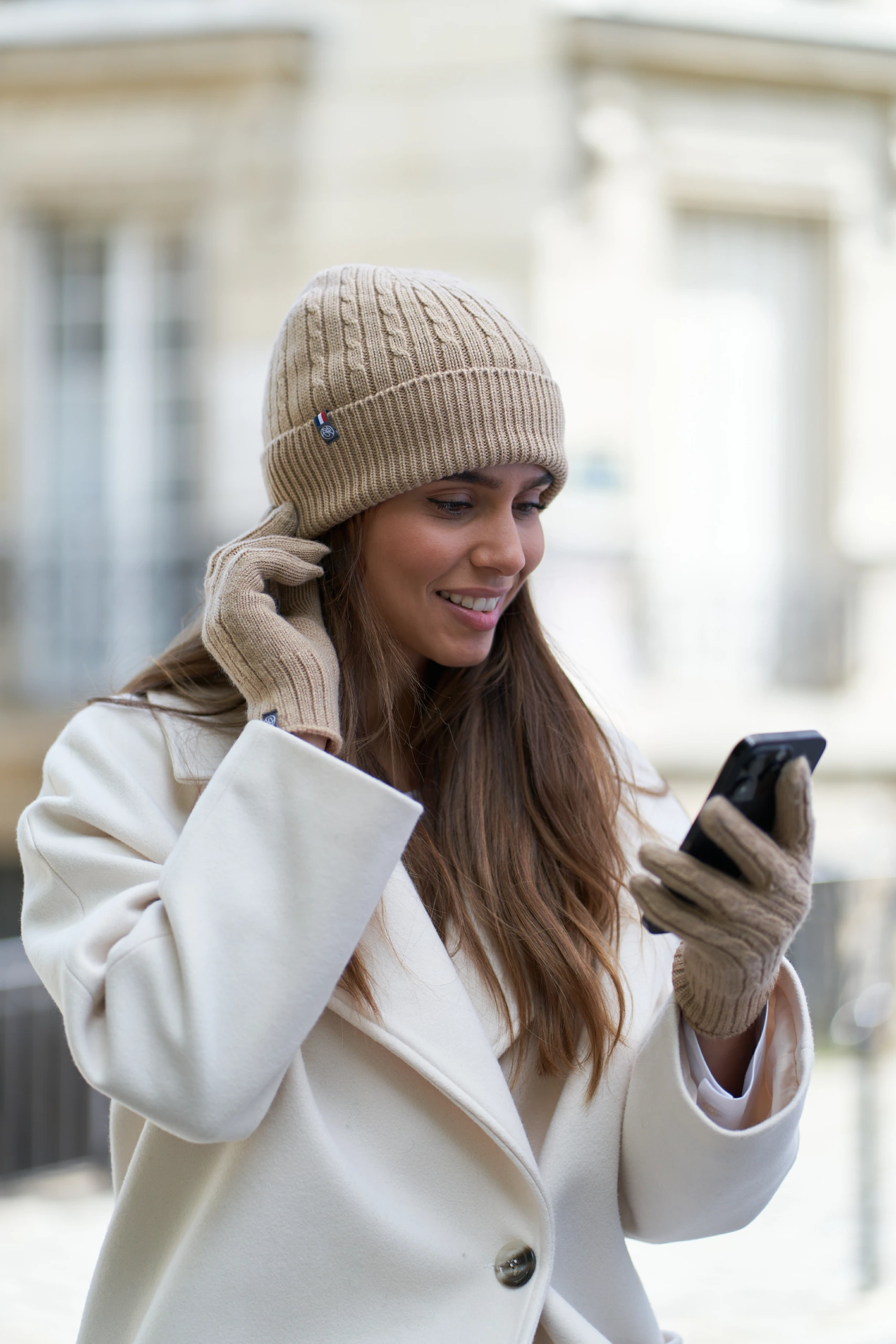 Portrait d’une femme portant un bonnet et des gants en laine beige de chez Maison Bonnefoy