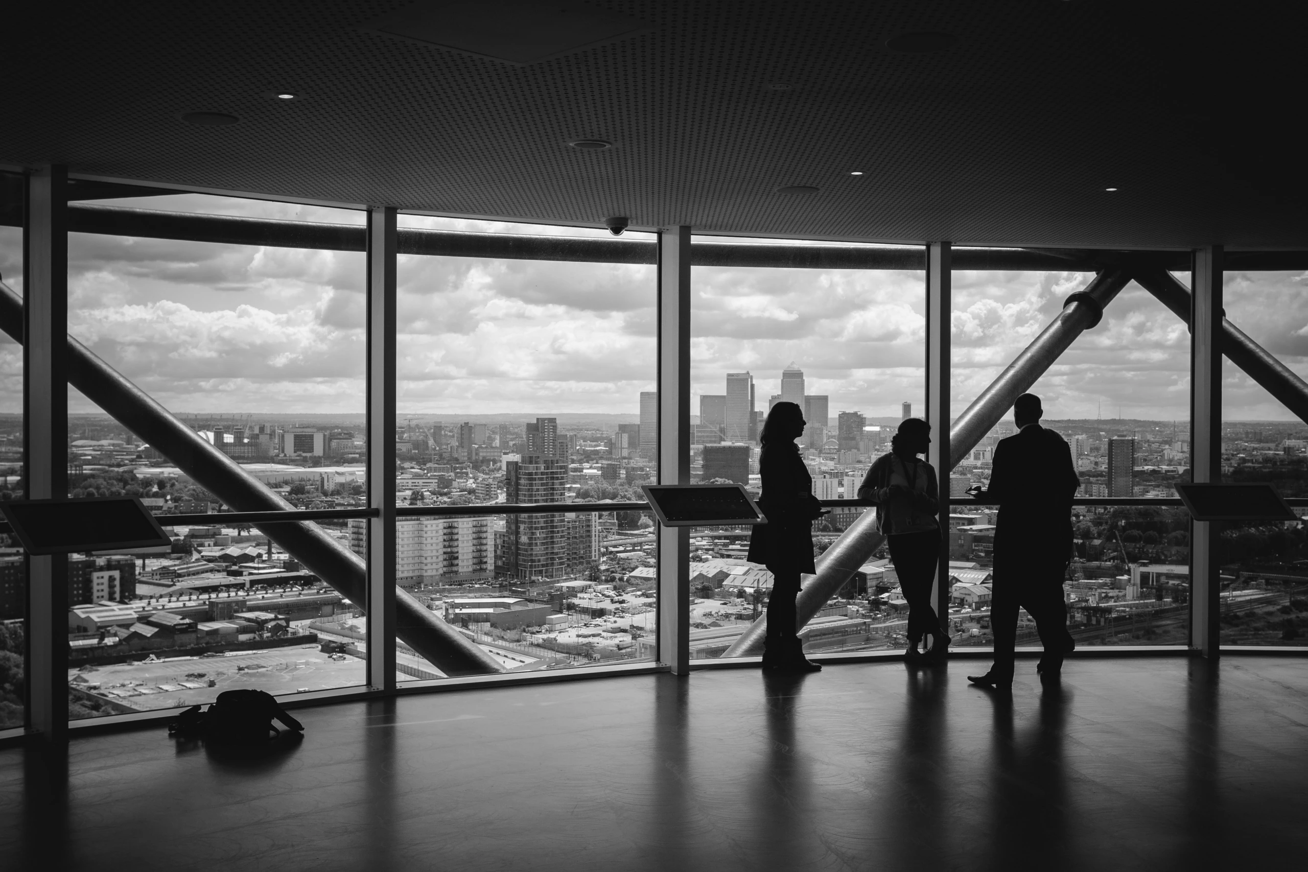 Trois personnes échangent dans une salle vitrée avec vue panoramique sur la ville