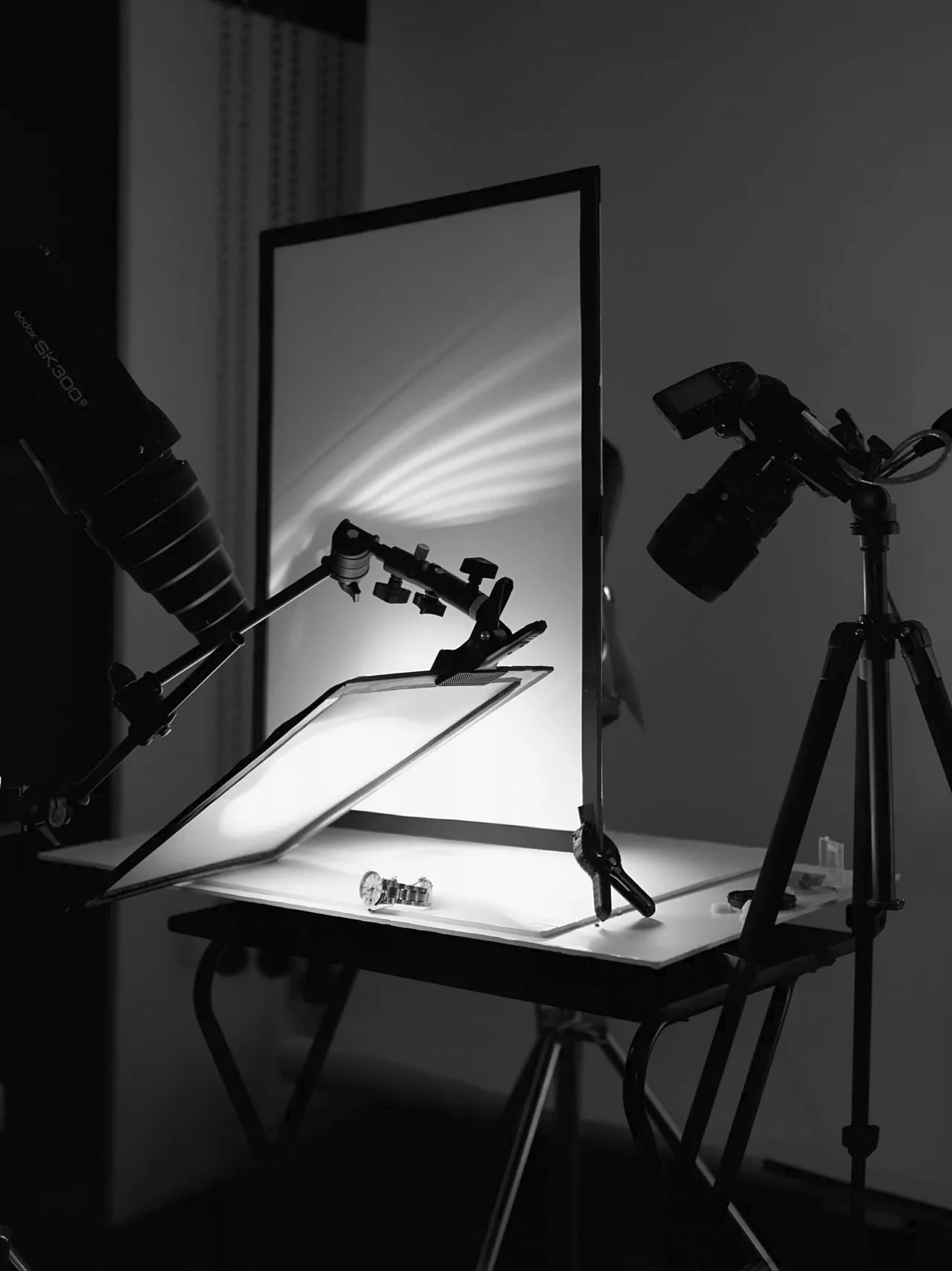 Studio professionnel avec deux appareils photo sur trépieds, panneau réfléchissant et éclairage contrôlé pour la photographie précise de produits à Nantes.