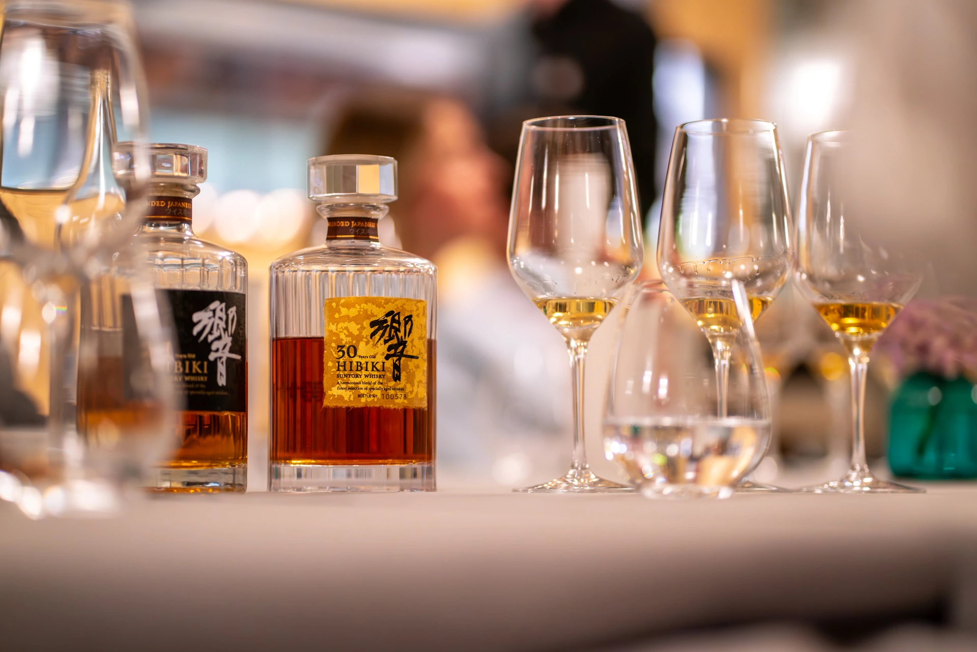 Deux bouteilles de whisky Hibiki et plusieurs verres de dégustation disposés sur une table.