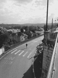 Photographie en noir et blanc d’un coureur solitaire sur une route en pente à Pau