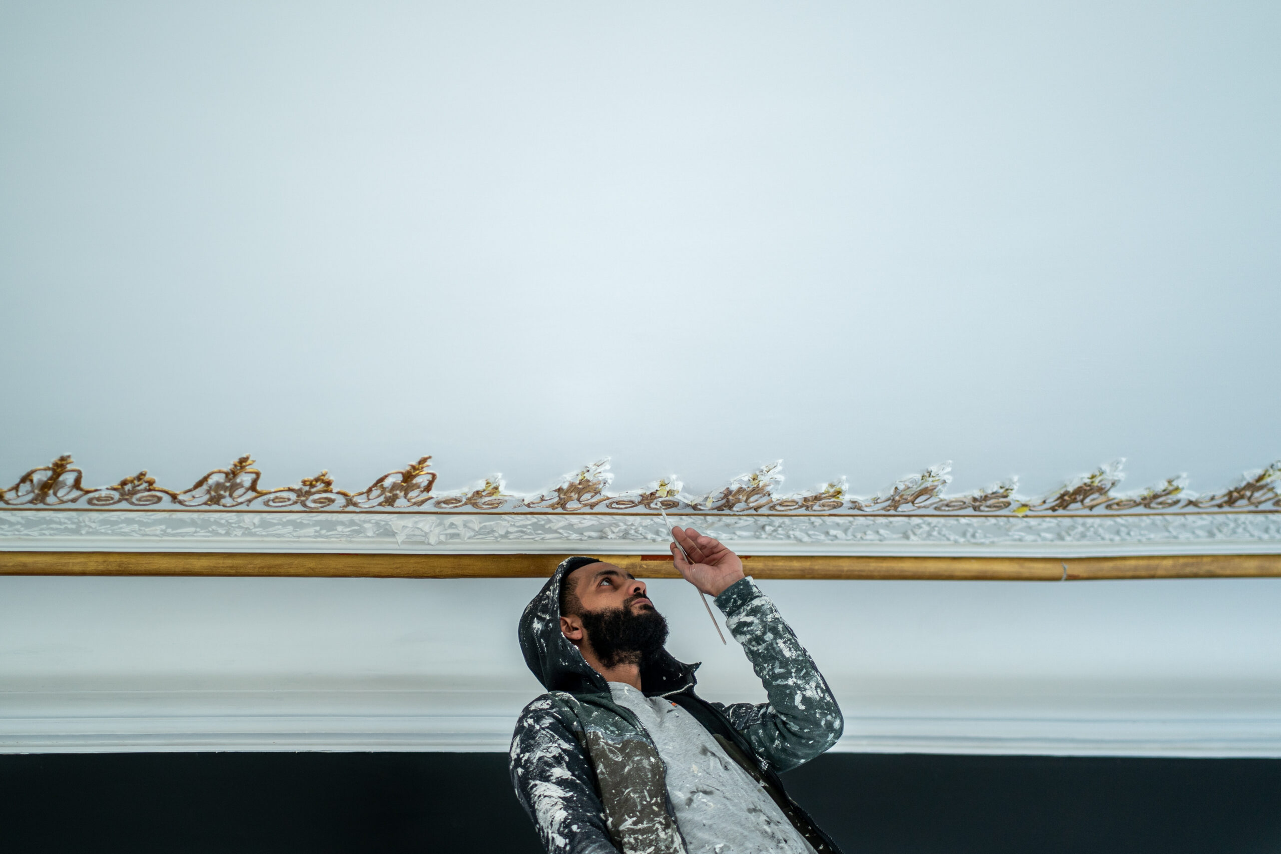 Photographie d'un artiste peintre qui rénove un plafond