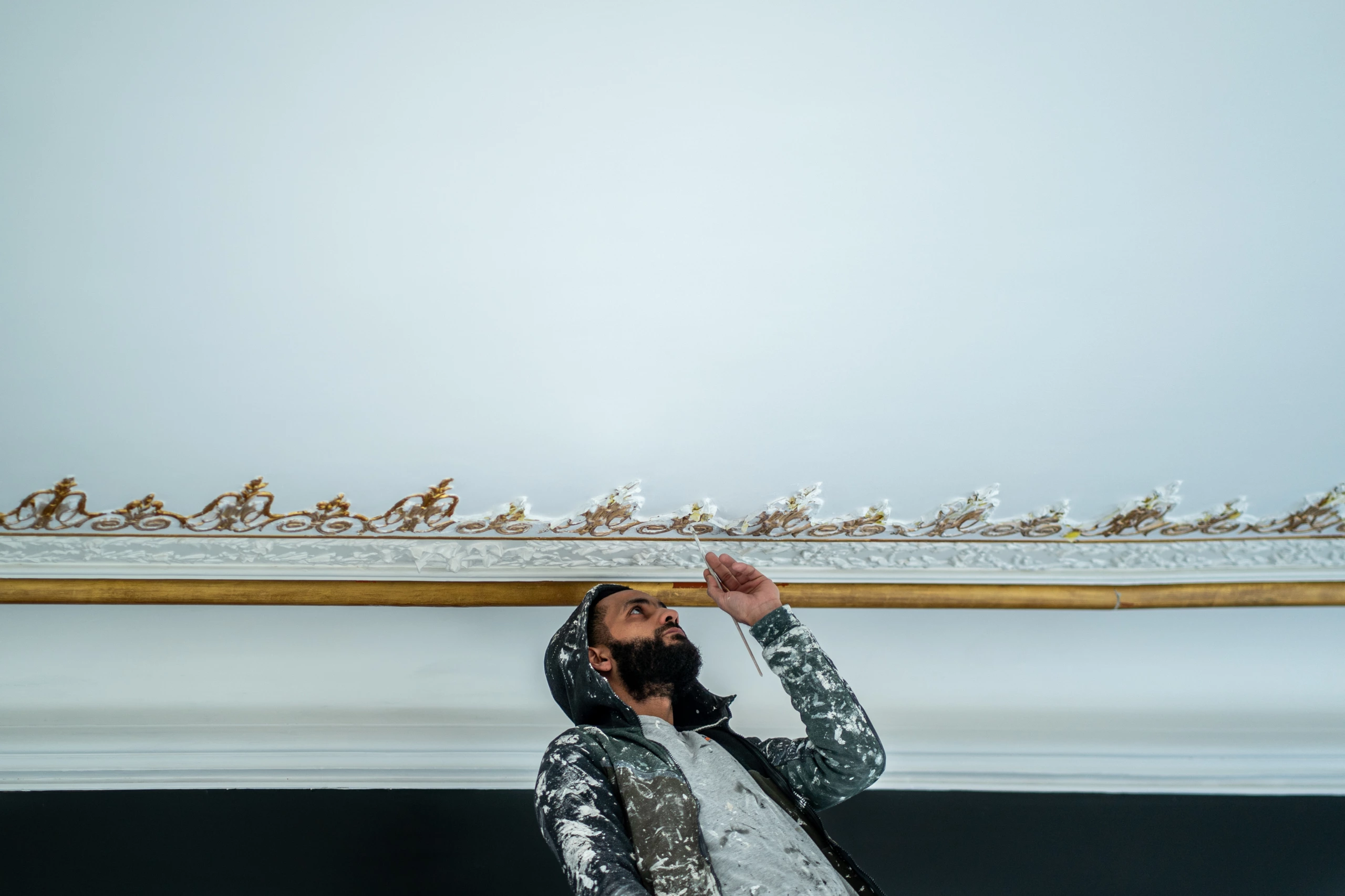 Photographie d'un artiste peintre qui rénove un plafond