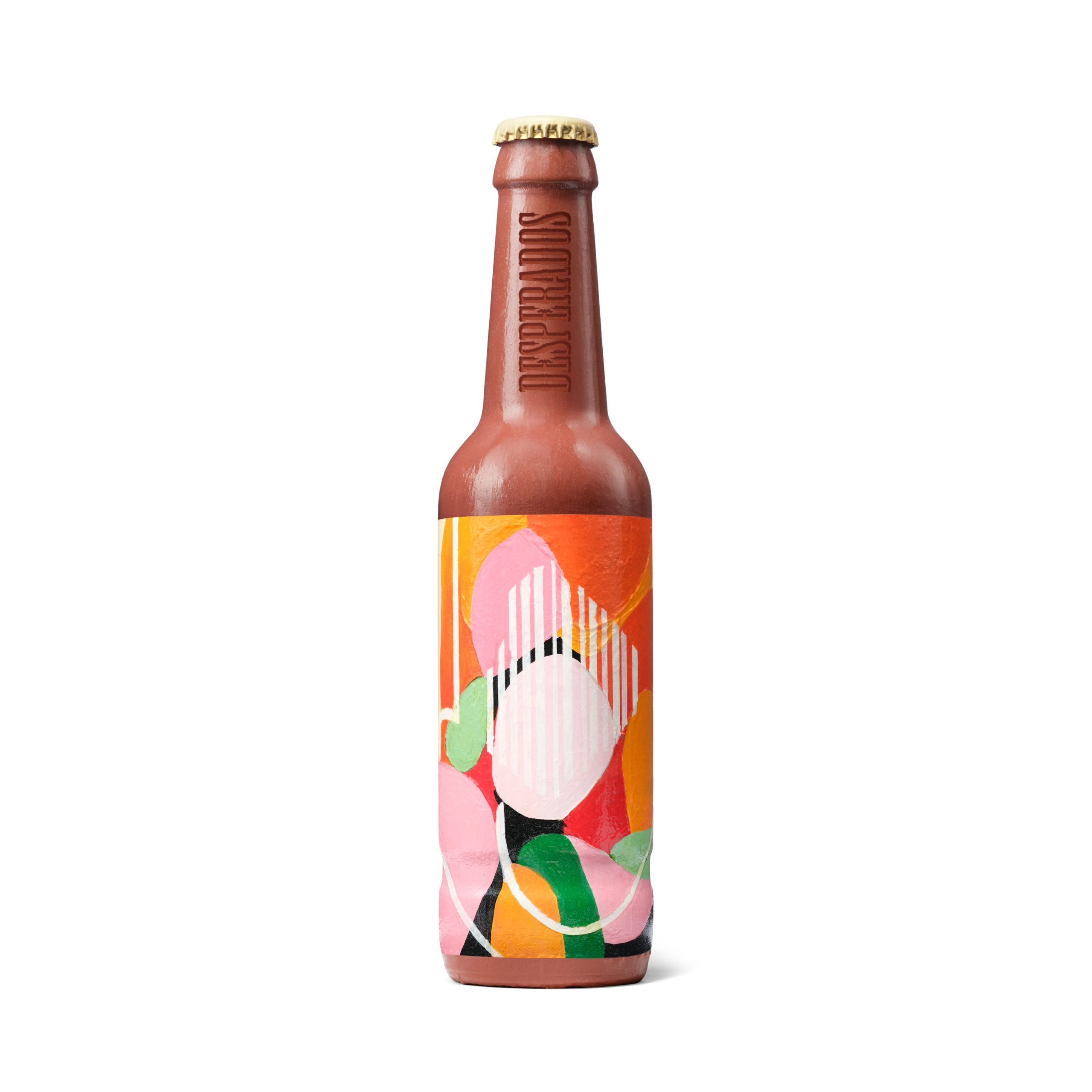Desperados_Packshot_Collector02 Une bouteille de bière en verre brun, munie d'un bouchon doré, est photographiée sur un fond blanc sans bordure. La bouteille porte une étiquette ornée de formes abstraites dans les tons rose, orange, rouge, vert et blanc. Un texte en relief est visible sur le goulot de la bouteille. Cette photo de produit met clairement en valeur les détails de l'emballage.