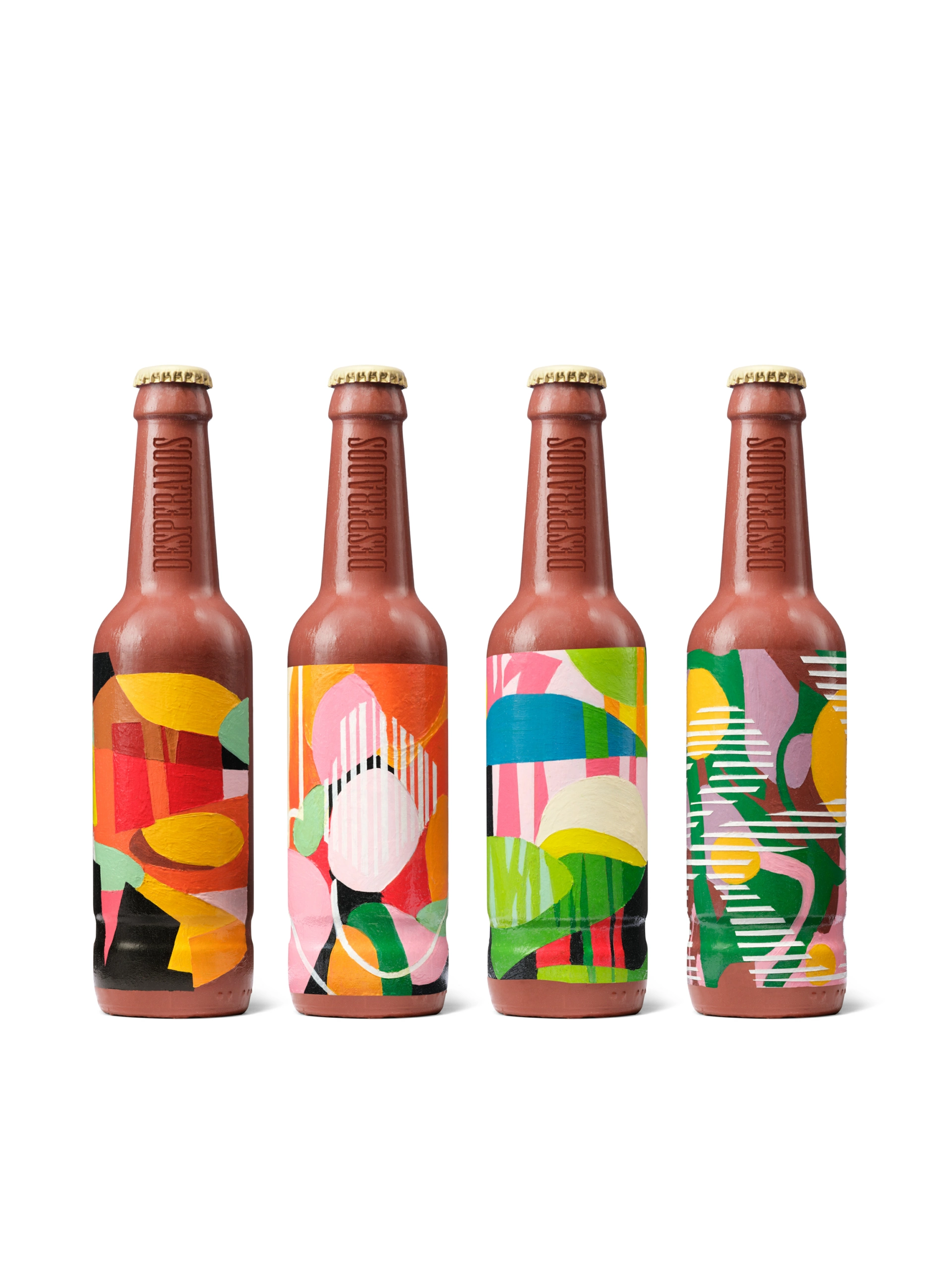 Une photo de studio montre quatre bouteilles de bière brunes aux capsules dorées, alignées en rangée. Chaque bouteille porte une étiquette unique et abstraite, ornée de motifs géométriques rouges, jaunes, verts, roses, blancs et bleus. La composition se détache sur un fond blanc homogène, ce qui permet de mettre en valeur le produit et d'assurer une grande clarté.